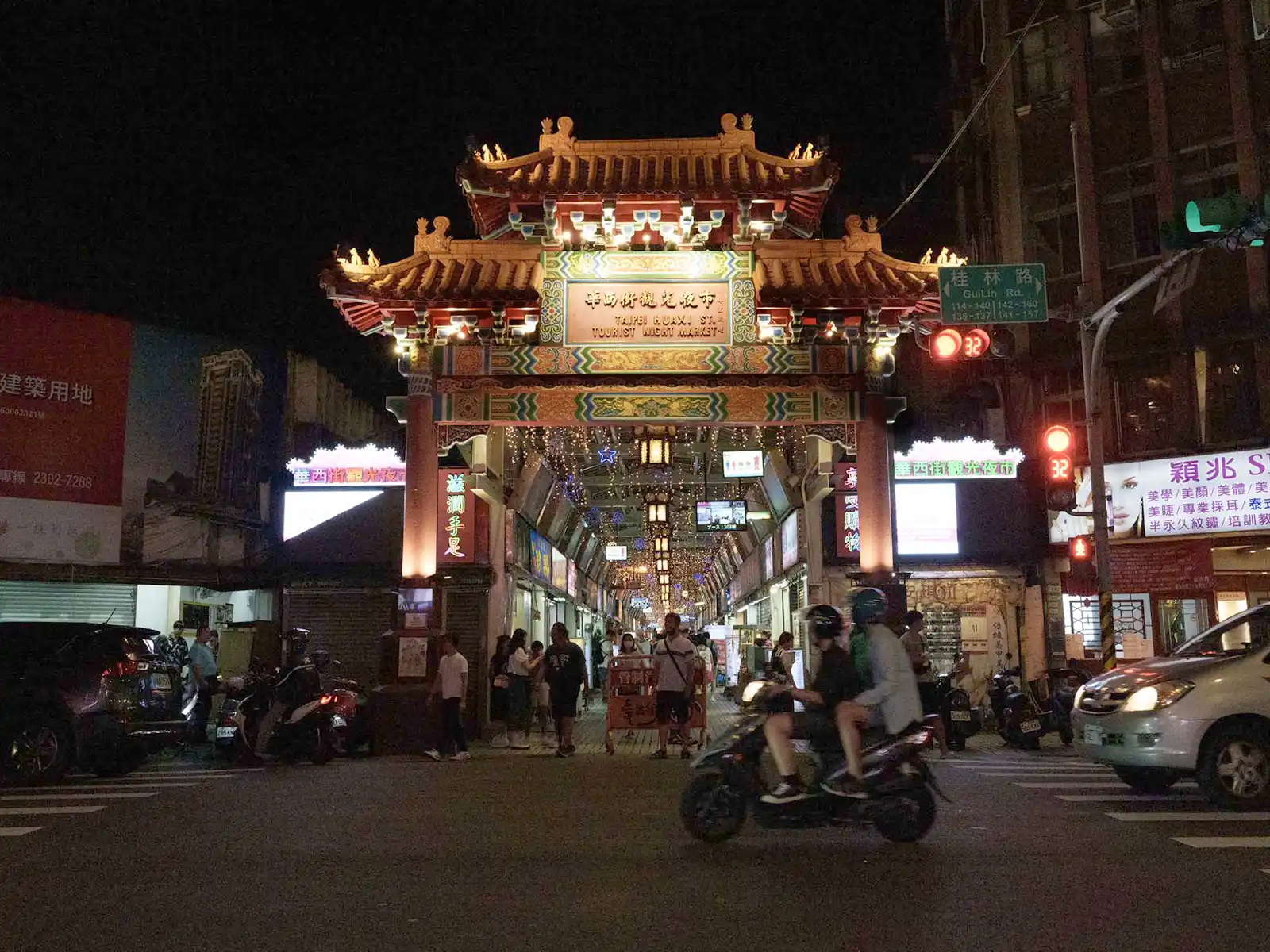 A traditional Chinese gate with bright decorations at the entrance of a Taipei night market.