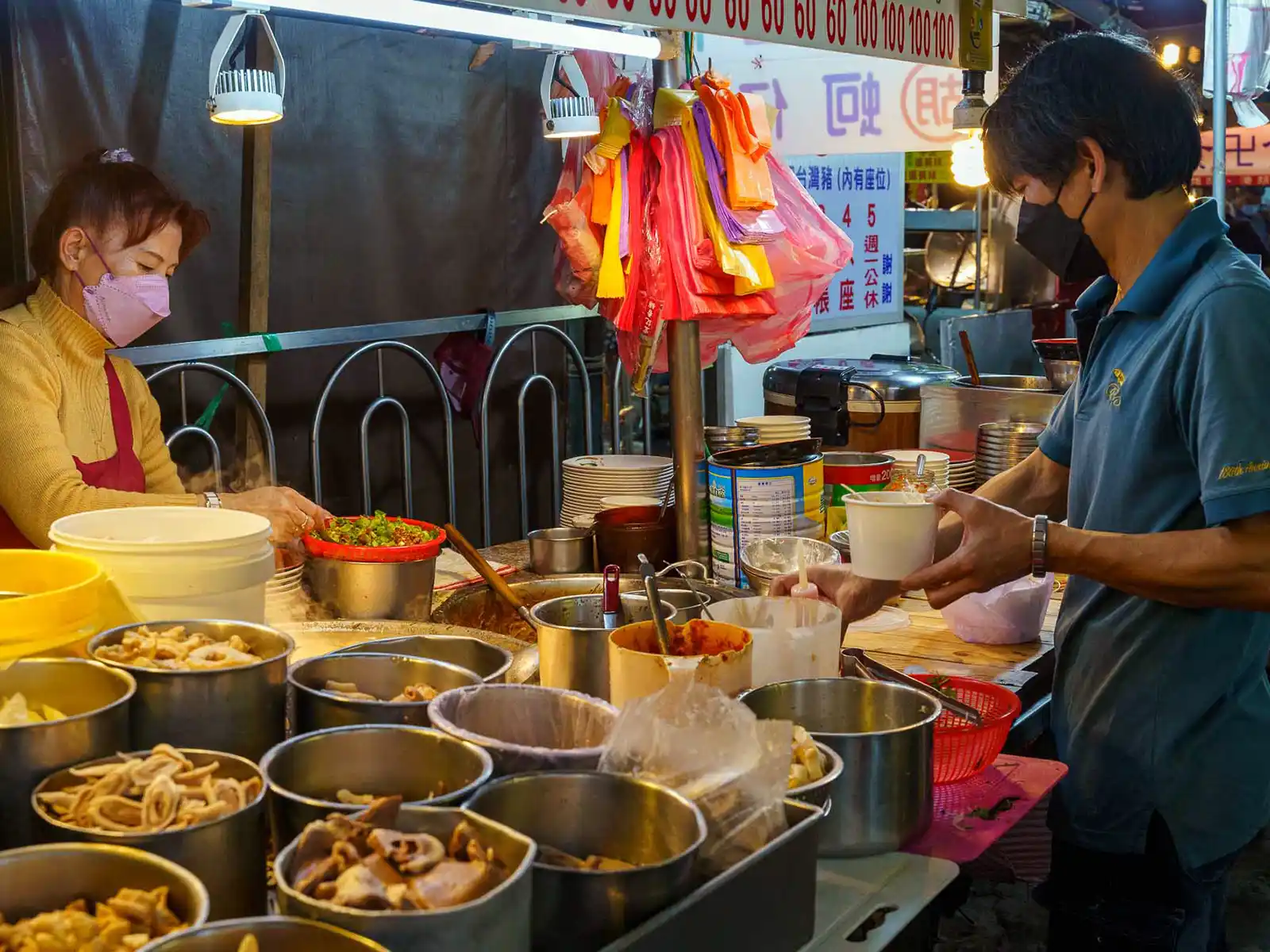 Stall owners serve customers amidst pots of ingredients at a Taipei night market.