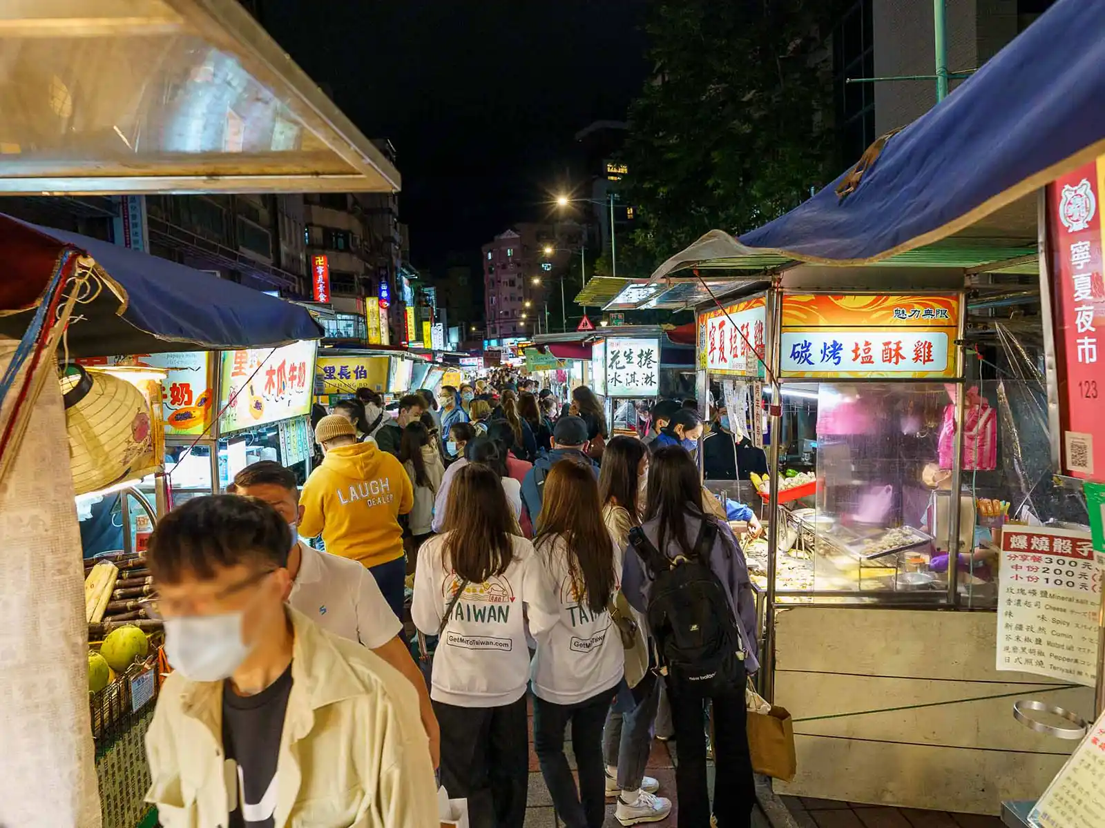 Crowded Taipei night market with visitors exploring various food stalls.