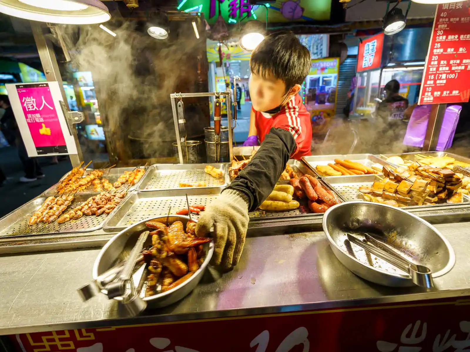 A vendor tends to an array of grilled meats at a bustling Taipei market.