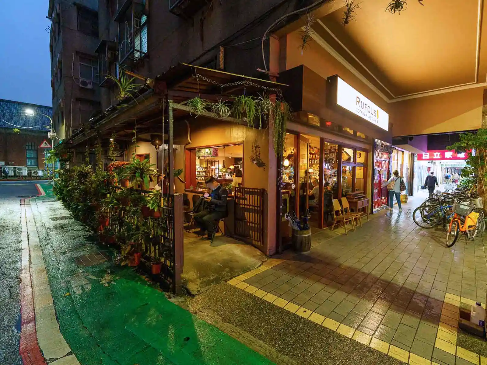 Night view of Rufous Coffee Roasters' exterior in Taipei, with warm lighting and potted plants.