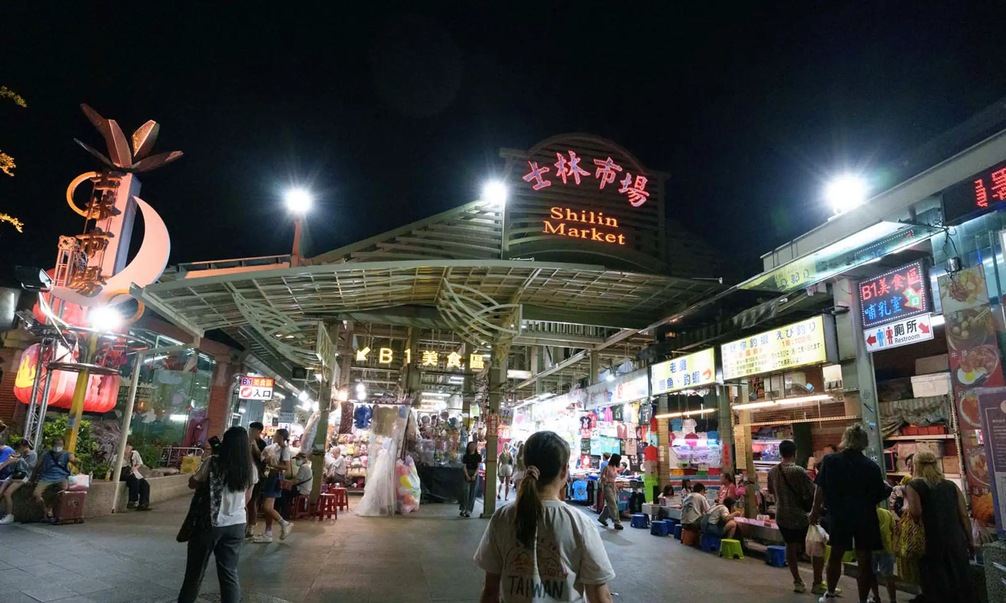 Entrance to Shilin Night Market with bright signage and visitors milling about.